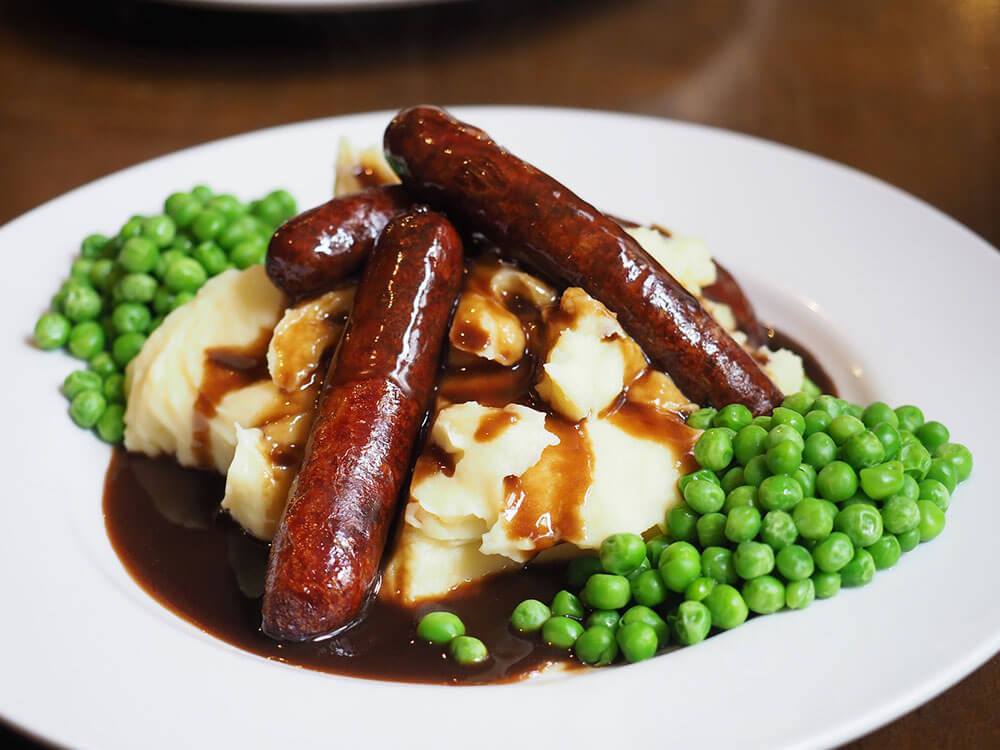 bangers and mash on a plate with peas