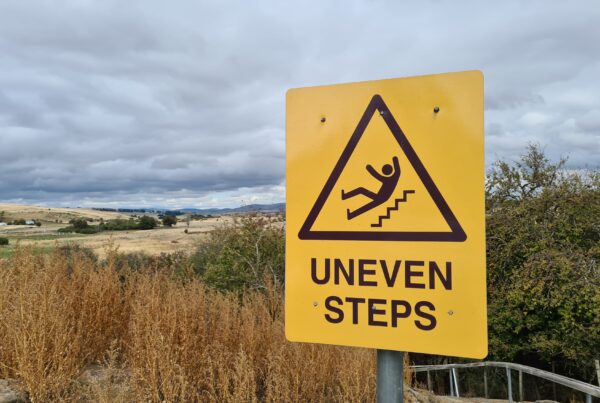 A sign reading "Uneven Steps" on a pathway down to the beach. The blog is about slip trip and fall cases.