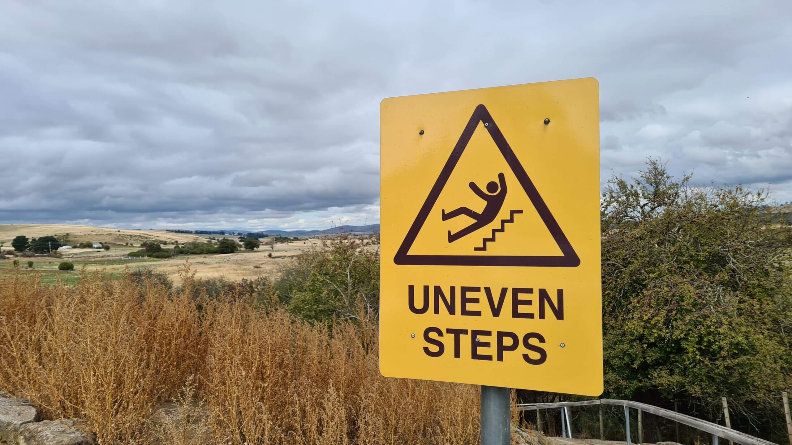 A sign reading "Uneven Steps" on a pathway down to the beach. The blog is about slip trip and fall cases.